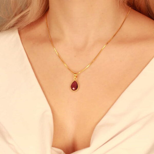 Detail van paarse amethist hanger aan goudkleurige ketting